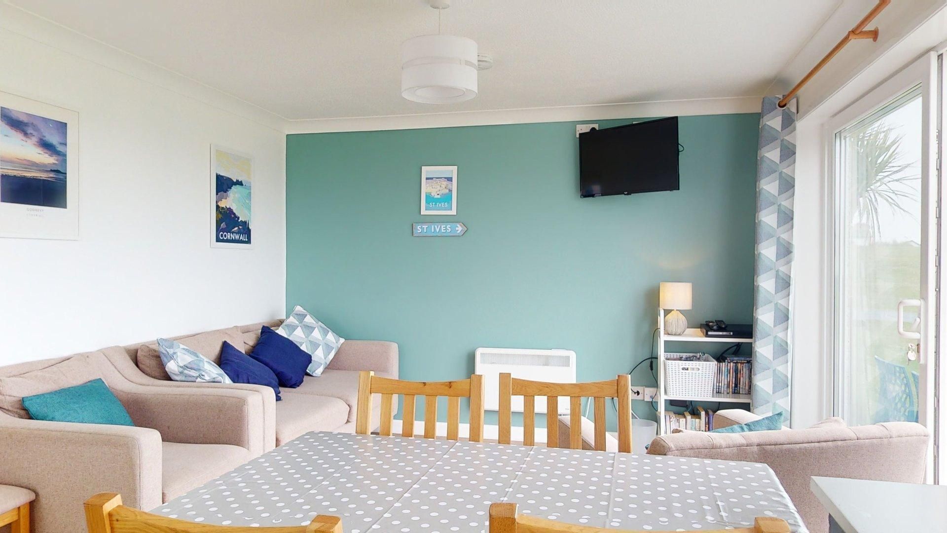 Un salon chaleureux avec un mur de couleur turquoise, un canapé, une table en bois et une bibliothèque.