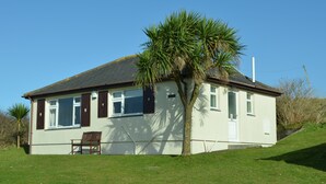 A single-story house with a white exterior, dark shutters, and a small porch. - D55 Wheal Lucy, Riviere Towans (Hayle)