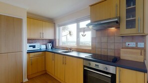 Eine Küche mit Holzausstattung, einer Mikrowelle, einem Toaster, einem Spülbecken und einem Fenster mit Blick.