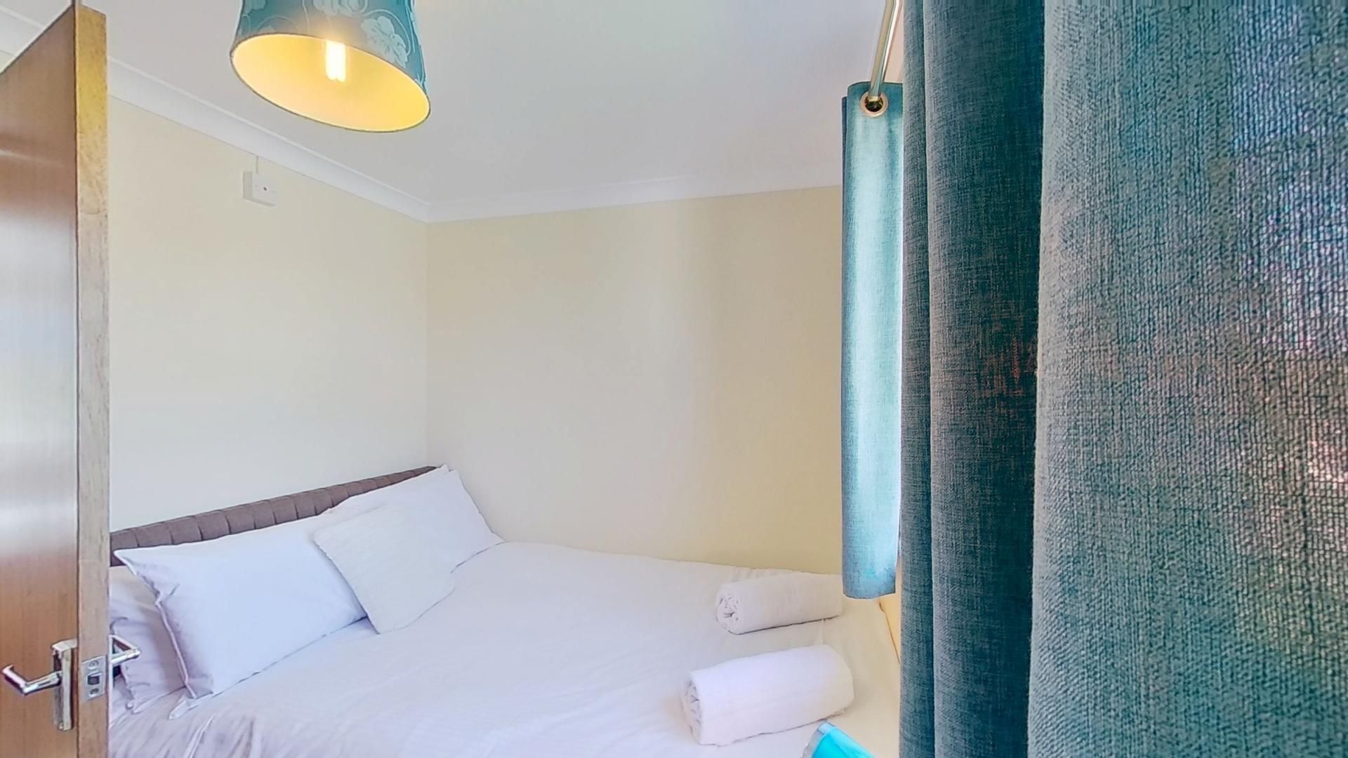 Ein Hotelzimmer mit einem Bett, einer Pendelleuchte und einem Vorhang.