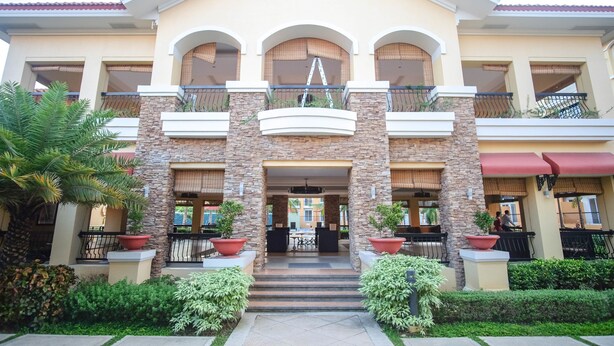 A hotel with a central entrance, multiple balconies, and a landscaped garden. - SR Vacation Rental - San Remo Oasis (Cebu City)