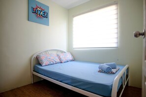 Cozy retreat with a single bed, striped pillow, and wall-mounted artwork.