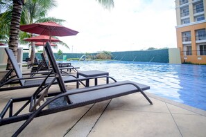Un espace piscine aménagé avec des chaises longues et des parasols.