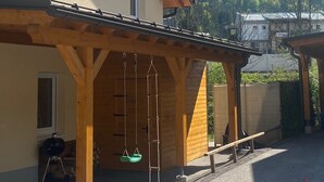 Rakennuksessa on puinen kuisti, ja siitä avautuu näkymä metsäiselle vuorelle.