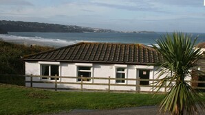 A coastal house with a tiled roof, white walls, and a wooden fence. - B38 Delamar, Riviere Towans (Hayle)