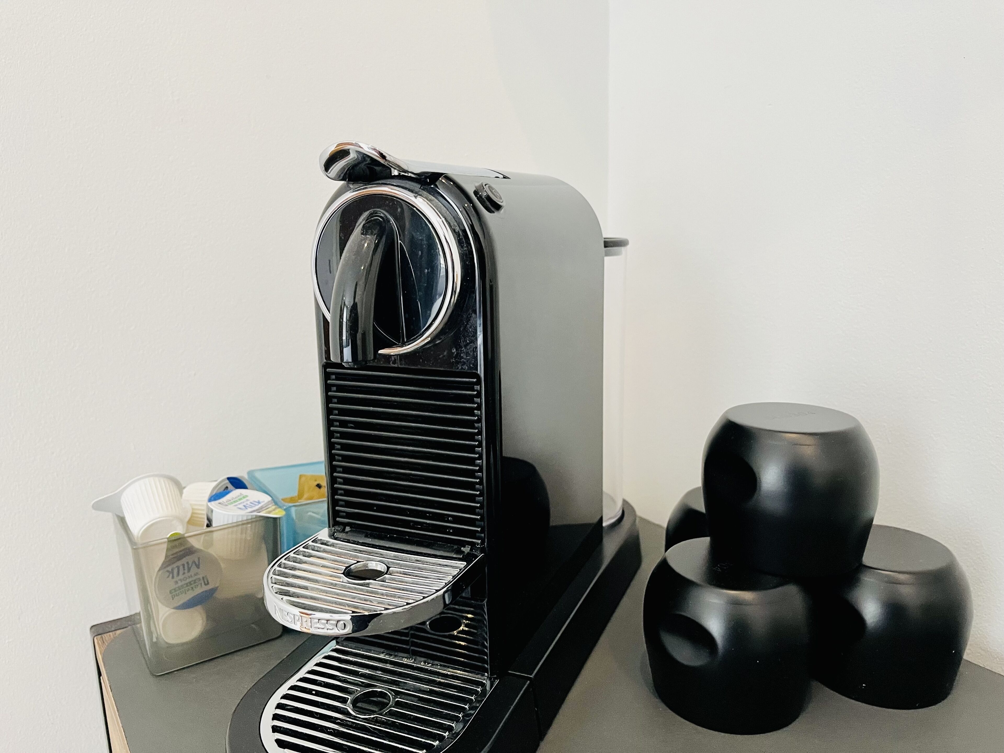 A compact espresso machine with a sleek, modern design, placed on a small table.
