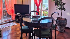 Un comedor con una mesa redonda, cuatro sillas, una planta en maceta y un televisor.