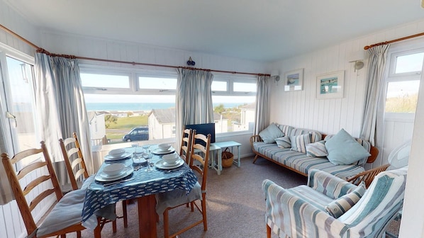 A cozy room with a dining table set for four, a sofa, and a TV.
