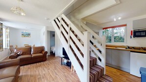 A modern interior with a staircase, a kitchen, and a living area with a leather sofa. - 37 Trevithick Court, Tolroy Manor (Hayle)