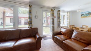 A living room with leather sofas, a dining table, and a view of the outside. - 37 Trevithick Court, Tolroy Manor (Hayle)