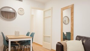 Ein modernes Wohnzimmer mit Holzboden, einem Esstisch mit Stühlen, einer Ledersofa, einem Spiegel und einer Uhr an der Wand.