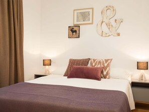 Un dormitorio con una cama, dos mesitas de noche, un adorno de pared grande y un mapa enmarcado.