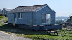 Une petite maison de plain-pied avec un porche à l’avant, une porte bien visible et une fenêtre.