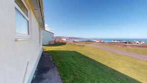 A coastal property with a grassy yard, a pathway, and a view of the sea. - B04 Beachcroft (B4), Riviere Towans (Hayle)