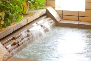 A water feature with a cascading design, surrounded by stone steps and a tiled wall.
