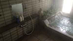 Un baño con ducha, espejo y una pequeña estatua.