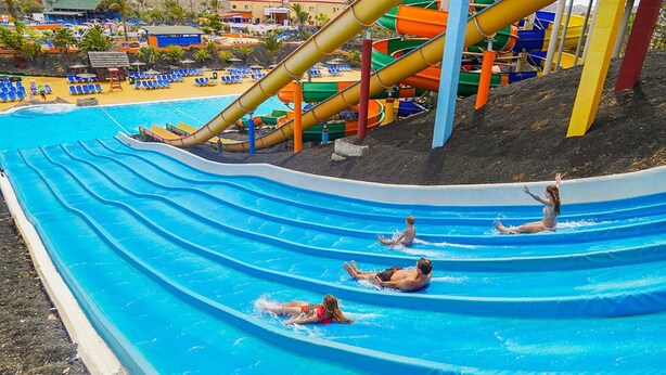 Un toboggan aquatique avec plusieurs pistes et des personnes qui dévalent la pente.