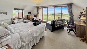 A spacious bedroom with a large bed, a desk, and a view of the countryside. - Splatt Barn, Porlock (Porlock)