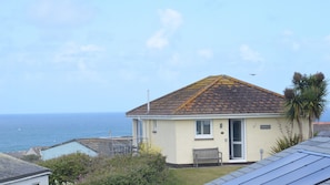 Une maison avec un toit en tuiles, un banc et une vue sur la mer.