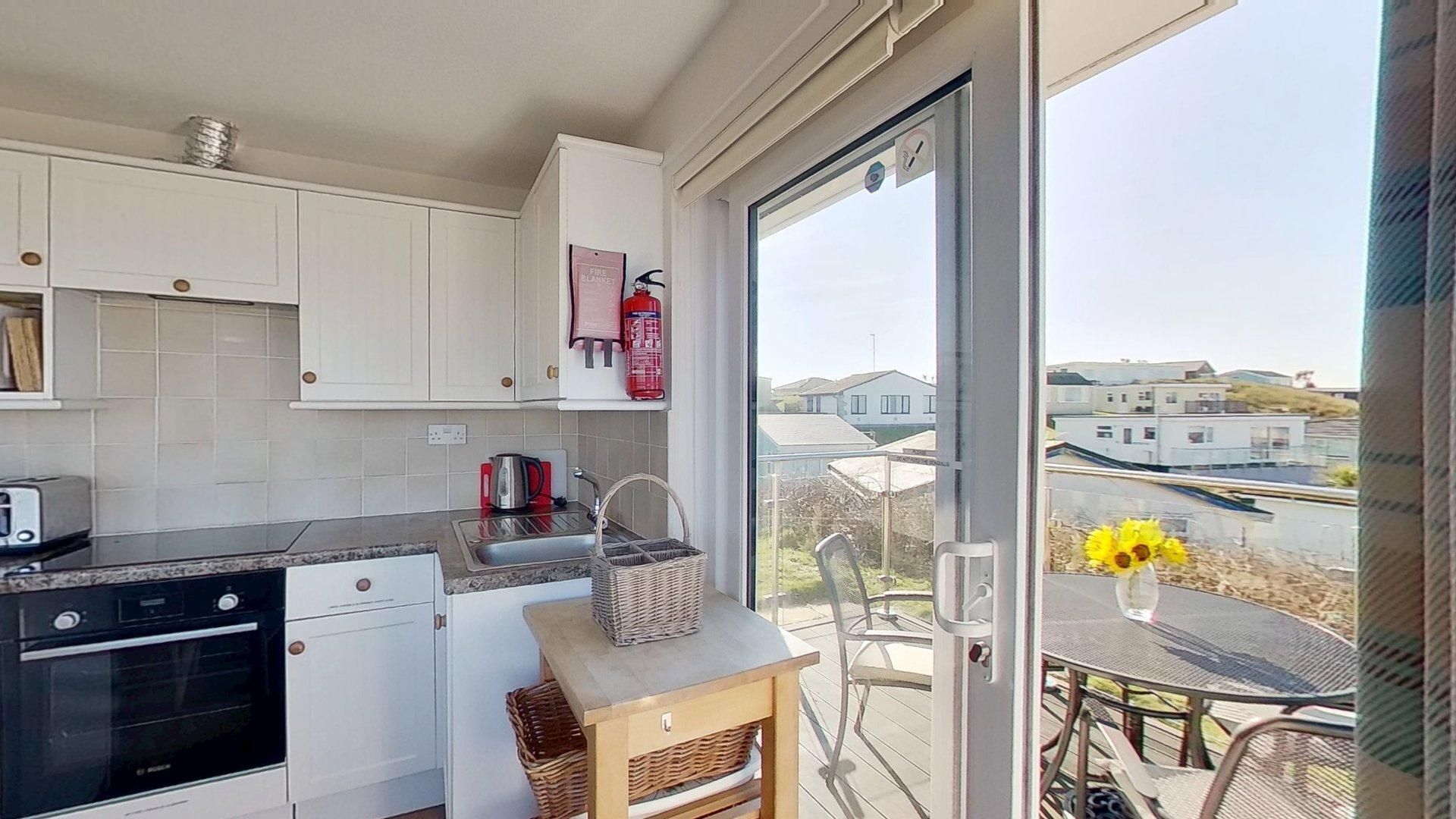 A modern kitchen with white cabinets, a black oven, and a red fire blanket on the wall.