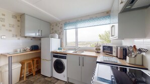 A compact kitchen with a washing machine, a microwave, a toaster, and a sink. - E17 Glenvale, Riviere Towans (Hayle)