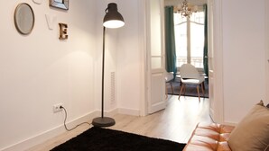 A modern living room with a black rug, a leather sofa, a standing floor lamp, and a chandelier. - Stylish apartment in city center 23 (Barcelona)