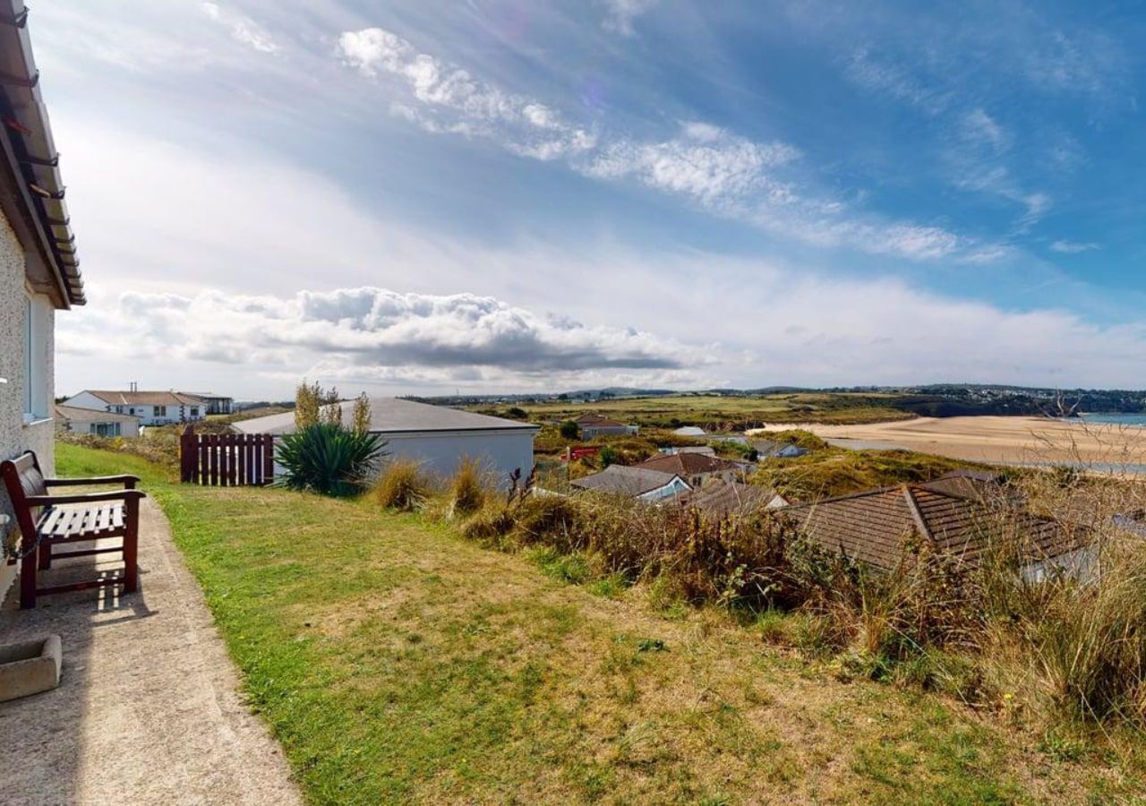 A coastal property with a grassy lawn, a wooden bench, and a small shed.