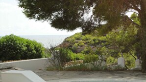 Ein Schwimmbecken mit Blick auf das Meer und eine Hügelkuppe.