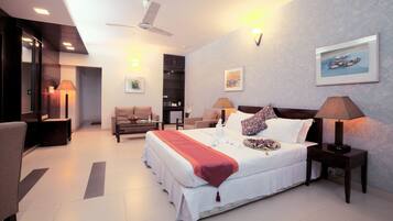 A modern hotel room with a large bed, bedside tables, a ceiling fan, and artwork on the walls.