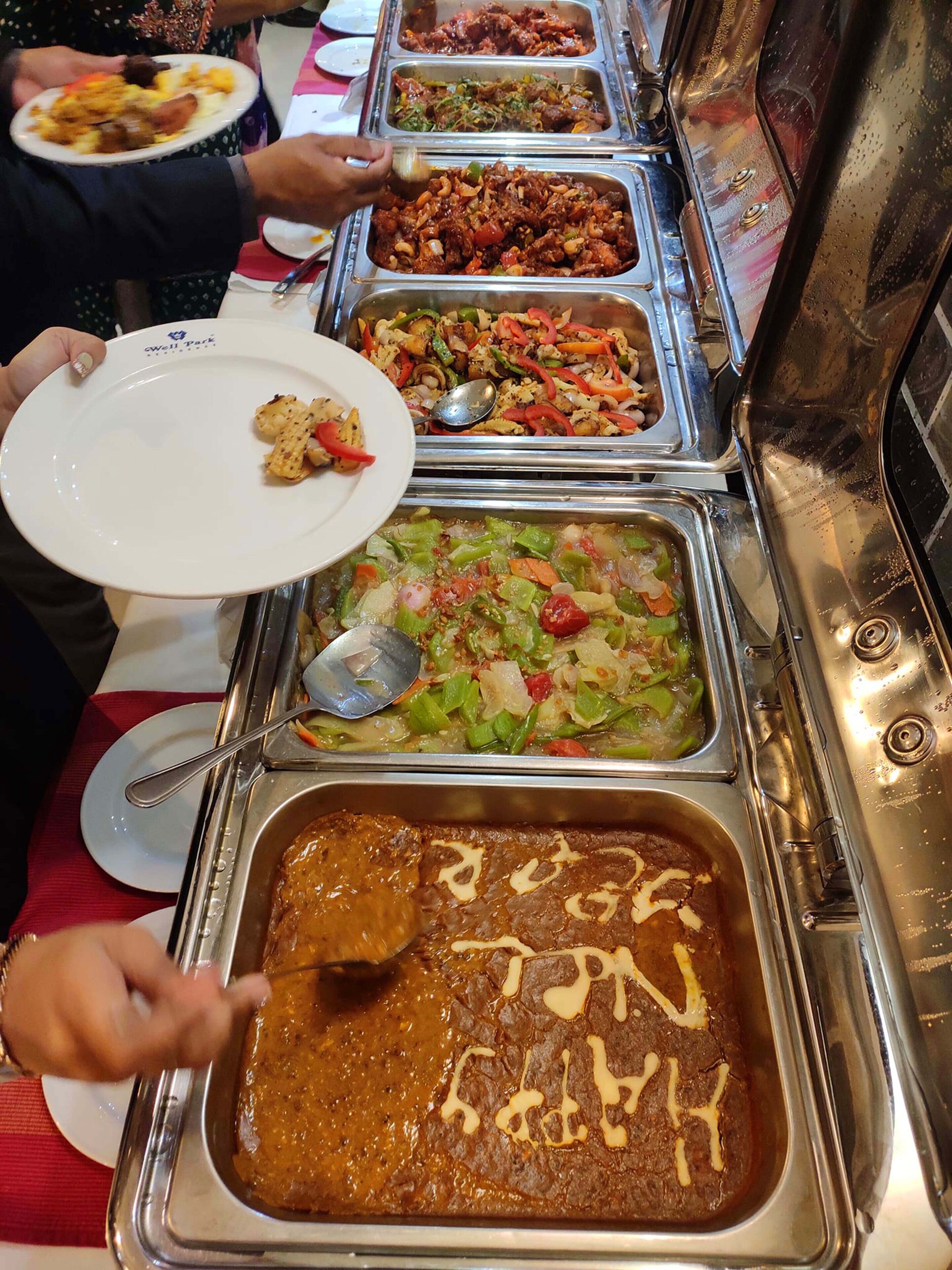 A buffet with various dishes, including a large tray of brownies and a salad.