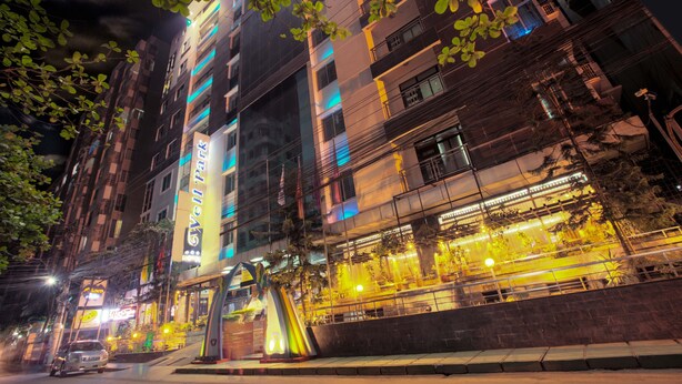A multi-story hotel with a prominent 'Gwell' sign, outdoor seating area, and a well-lit facade. - Well Park Residence Boutique Hotel (Chittagong)
