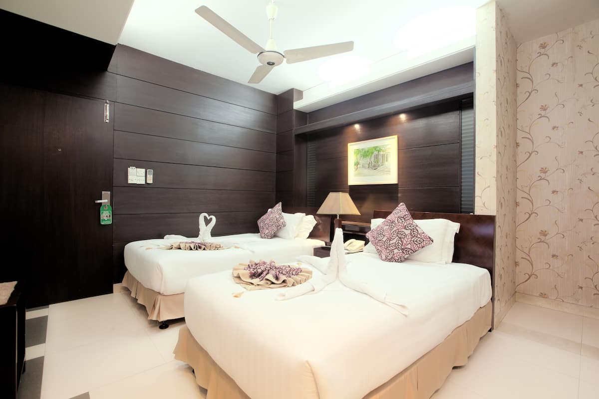 A hotel room with two beds, a ceiling fan, a nightstand, and a framed picture on the wall.
