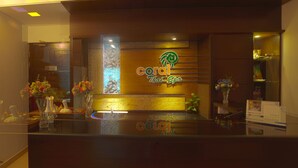 A reception area with a wooden counter, a neon sign for Coral Thai Spa, and decorative vases with flowers. - Well Park Residence Boutique Hotel (Chittagong)
