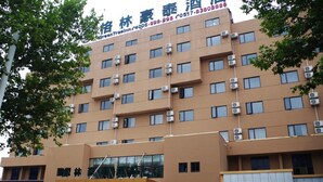 A multi-story hotel with a brown facade, air conditioning units, and a signboard with Chinese characters. - GreenTree Inn HuaiAn Bus Terminal HuaiHai NorthRoad Hotel (Huai'an)