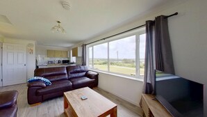A living room with a sofa, a coffee table, a TV, and a view of the outdoors. - D56 Beachcomber, Riviere Towans (Hayle)