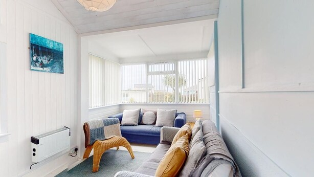 A bright room with a blue sofa, a wicker chair, and a radiator. - D34 Homeleigh, Riviere Towans (Hayle)