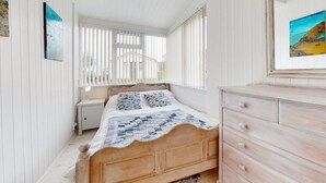 A bedroom with a wooden bed, a nightstand, a dresser, and a window with blinds. - D34 Homeleigh, Riviere Towans (Hayle)