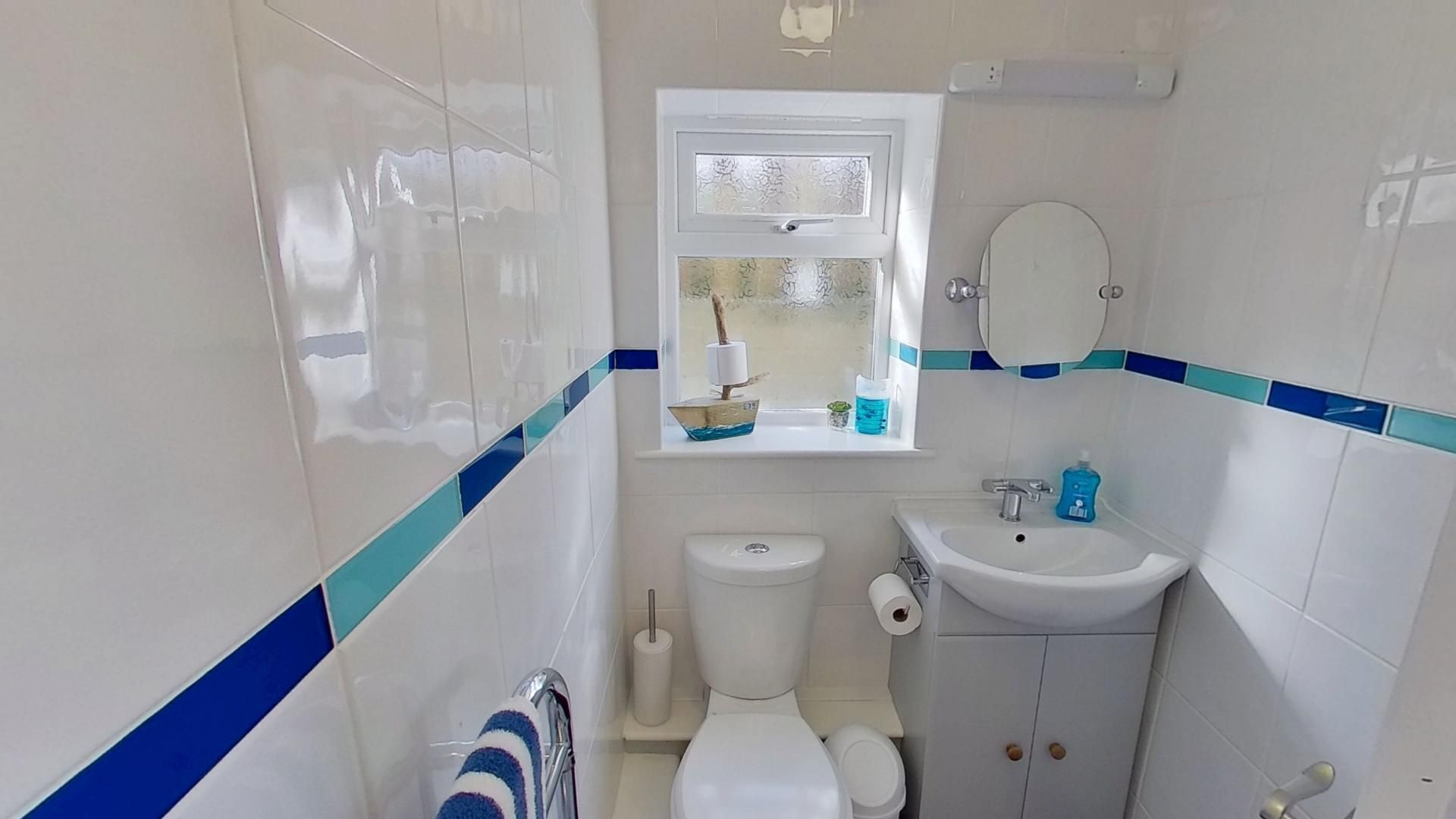 A small bathroom with a toilet, sink, and window.