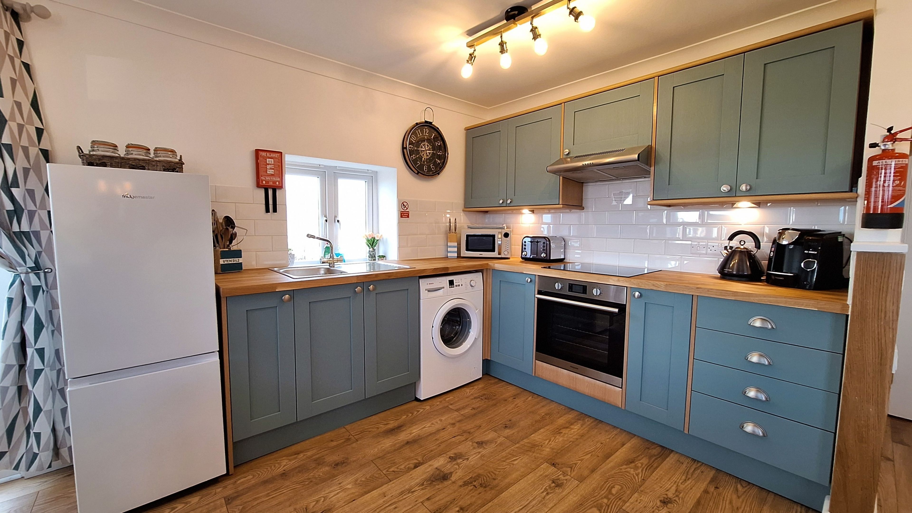A compact kitchen with a washing machine, microwave, toaster, and coffee maker.