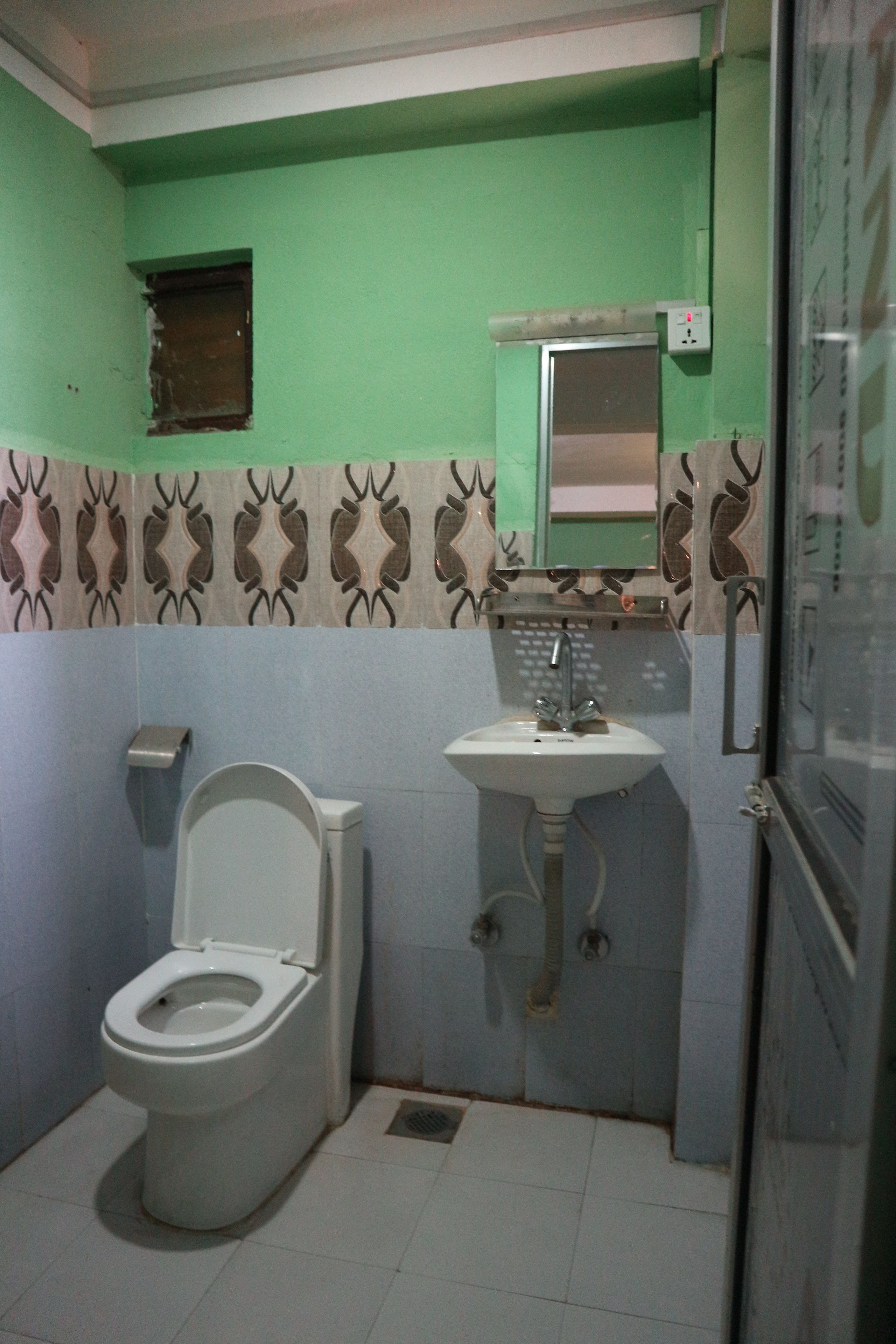 A small bathroom with a toilet, sink, and a mirror.