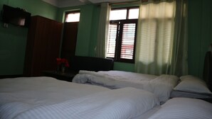 A room with two beds, a television on a stand, and a window with curtains. - Hotel Peace Mountain (Kathmandu)