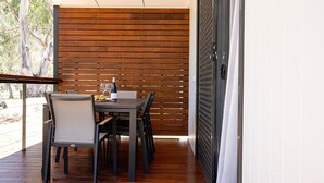 Een eetgedeelte met een houten tafel en stoelen, een glas wijn en een schaal fruit.