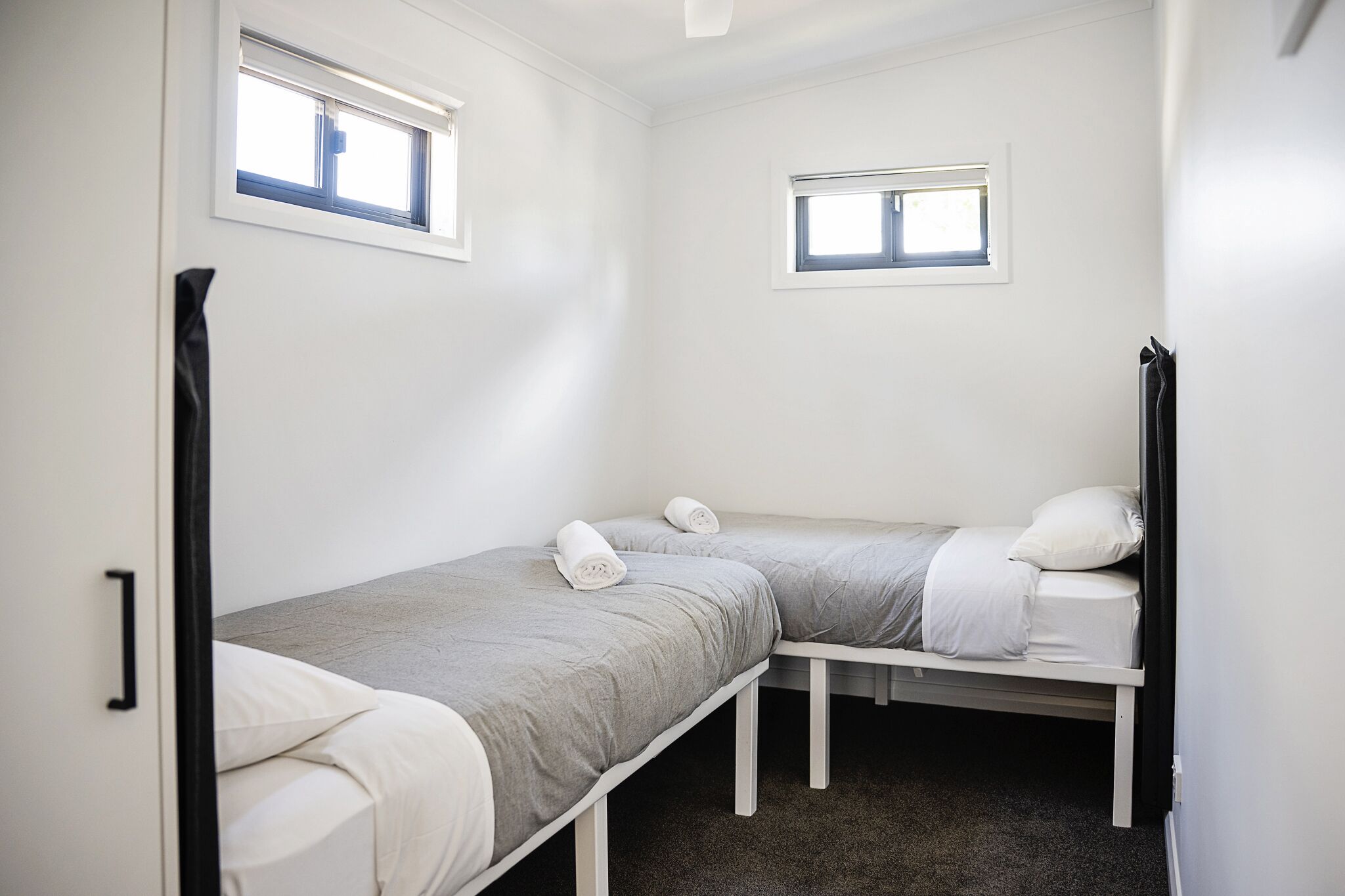 Une petite chambre propre, avec deux lits simples, une fenêtre et une porte.