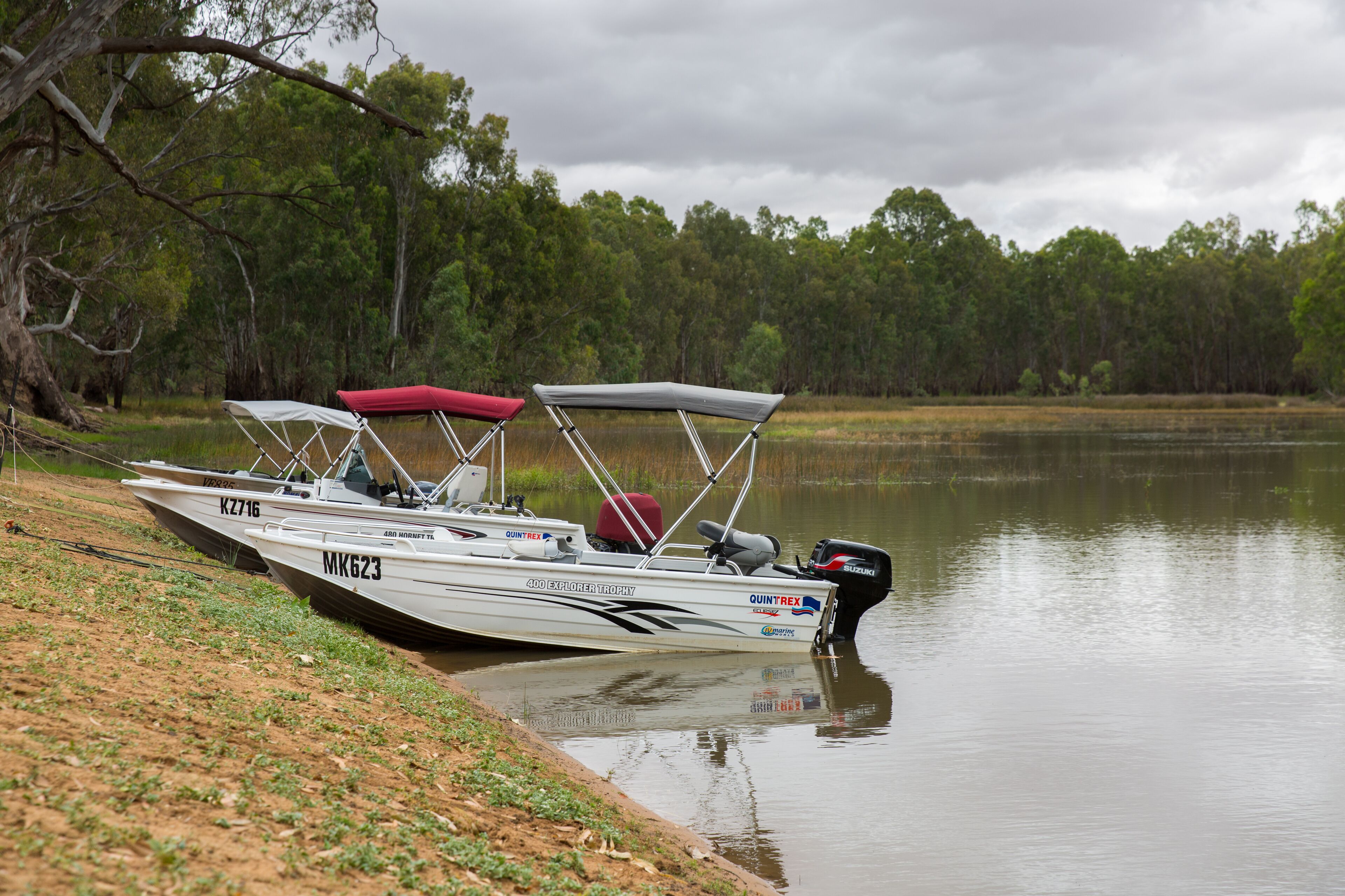 A boat docked at a lakeside with a forest in the background.