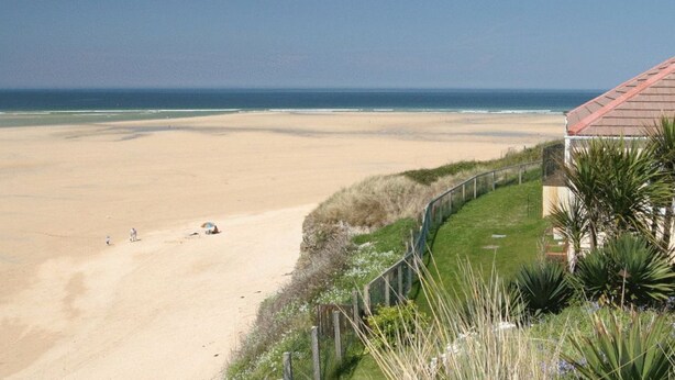 A beach view with a house and a fence.