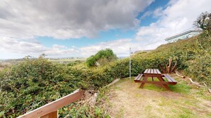 A picnic table in a natural setting with a view of the countryside.
