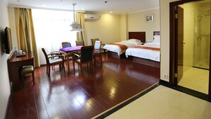 Habitación de hotel con dos camas, un escritorio con sillas, televisor y zona de ducha.