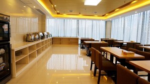 Un comedor moderno con mesas y sillas de madera, una barra con equipo de cocina y ventanas amplias con cortinas translúcidas.