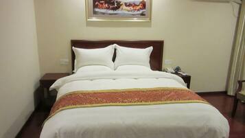 A hotel room with a large bed, a nightstand, a framed picture on the wall, and an air conditioning unit.