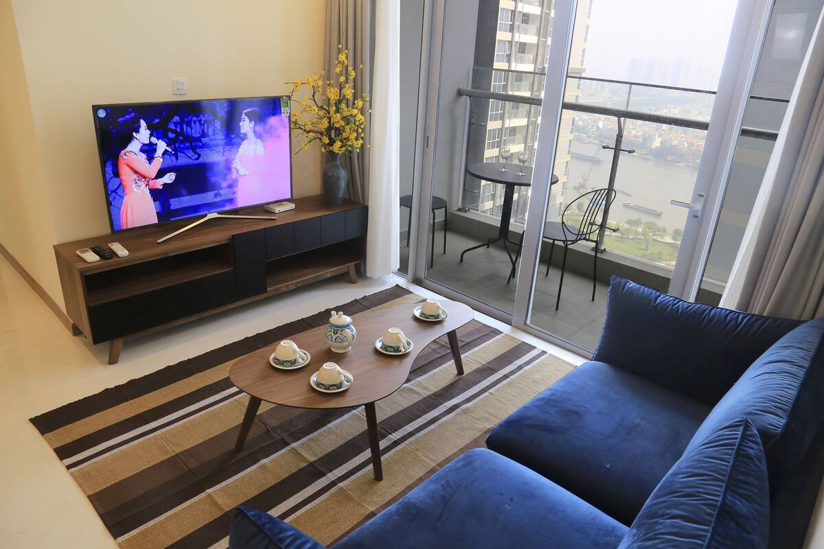 Een woonkamer met een televisie, bank, salontafel en een balkon met uitzicht.